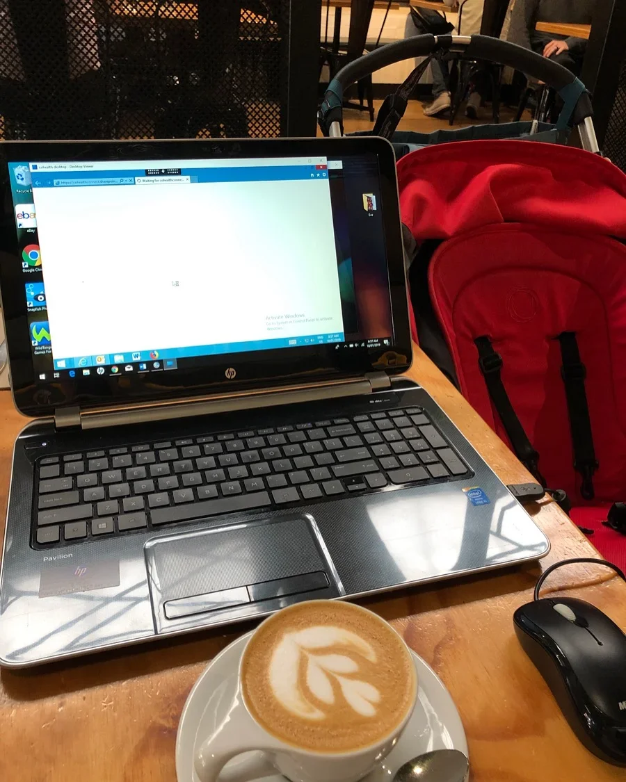 Working in cafe on laptop with coffee and baby