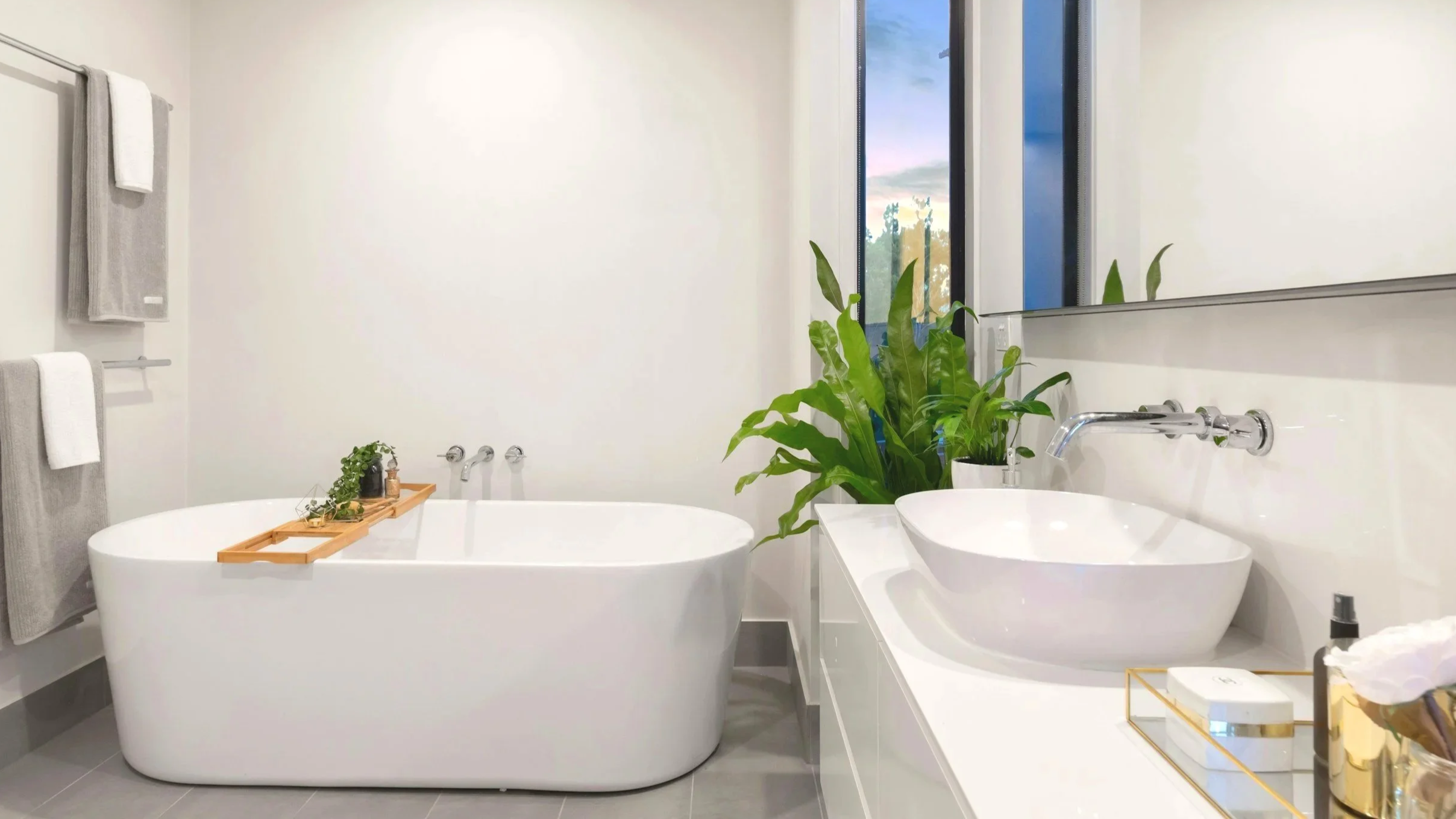 A Sydney bathroom renovation with a white bathtub and a double sink with a large mirror.