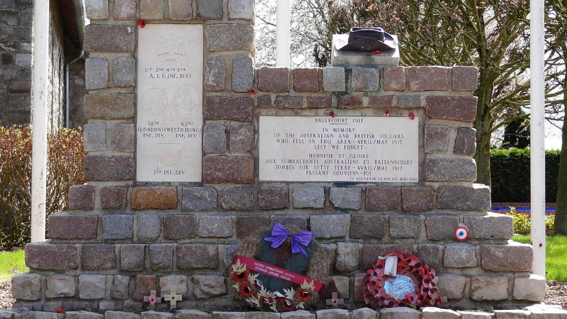 Stone memorial with wreaths and plaques commemorating Australian and British soldiers from 1917. Surrounded by trees and grass.