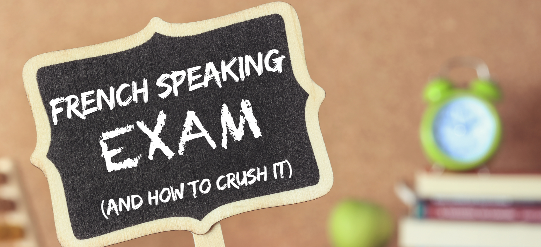 Chalkboard sign reading "French Speaking Exam (and how to crush it)" with books and a clock in the background — VCE French oral exam tips blog