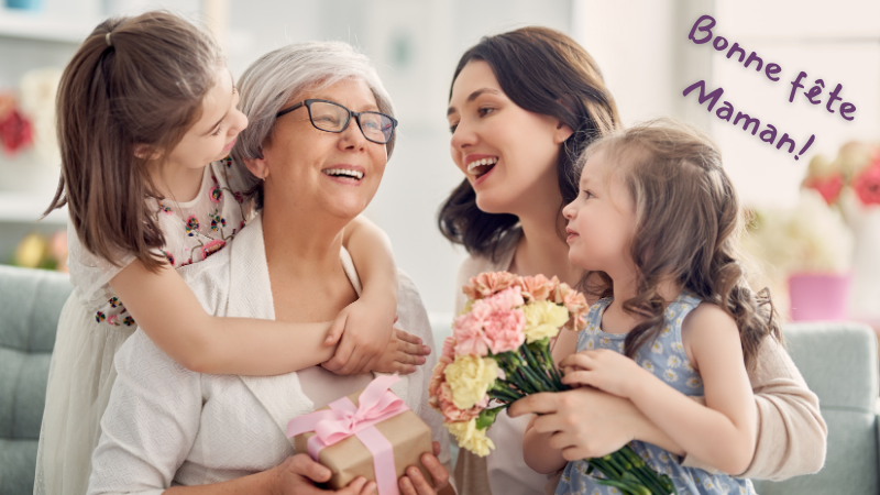 Three generations of women celebrating; the grandmother holds a gift, and a child has flowers. "Bonne fête Maman!" text in the background.