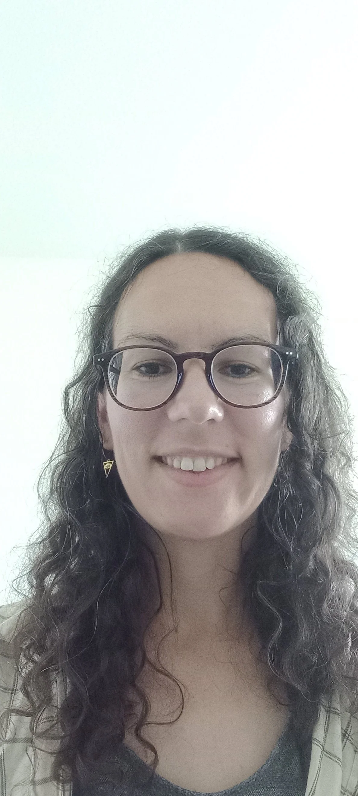 Camille, French teacher at Sophie French Tutor, smiling with curly hair and glasse