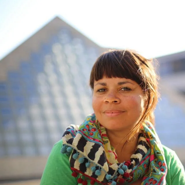 Saly, French teacher at Sophie French Tutor, smiling outdoors wearing a colourful patterned scarf