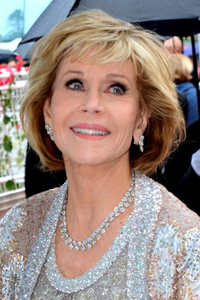 American actress and activist Jane Fonda smiling at a public event, wearing a sparkling silver outfit and diamond jewellery.