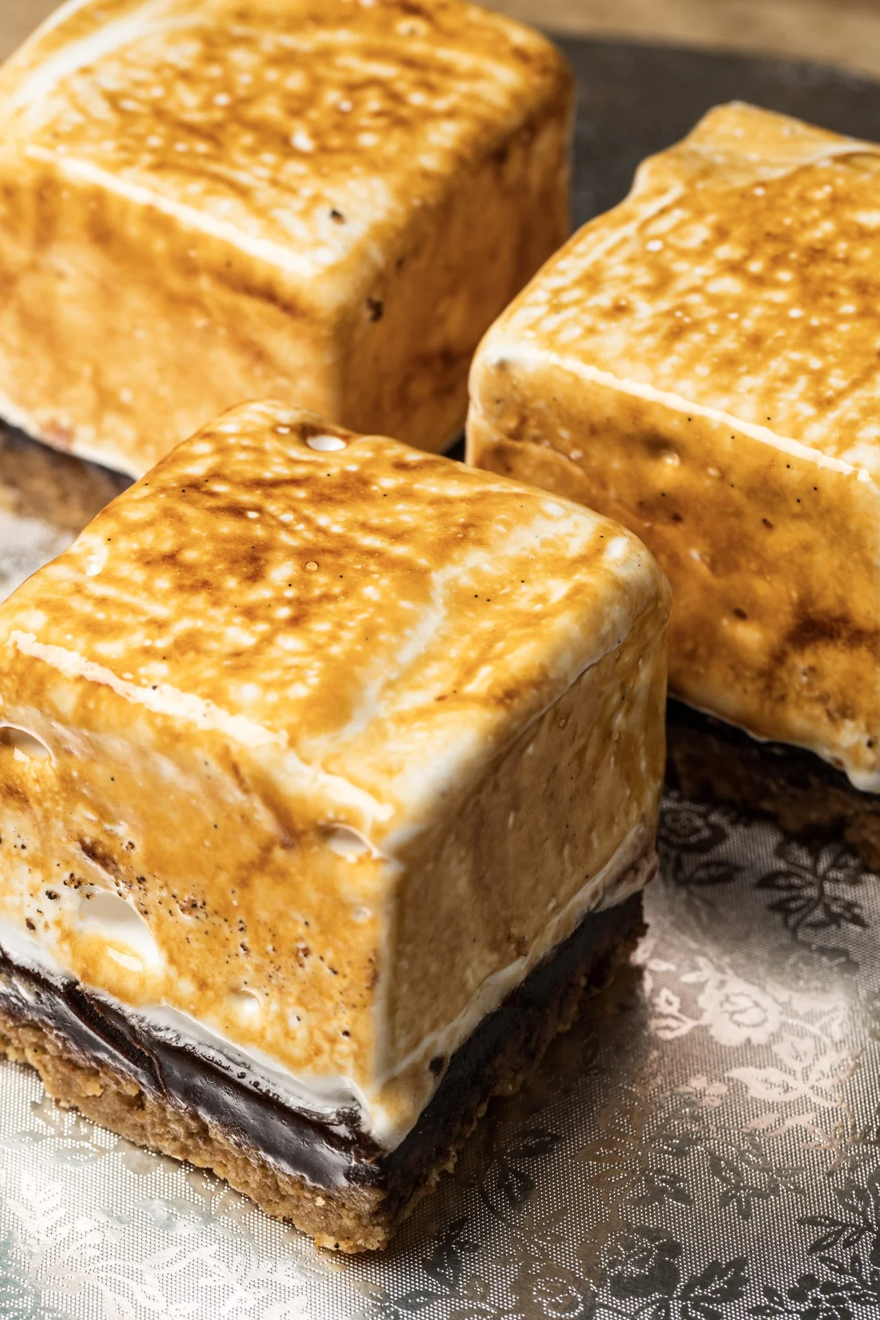 Close-up of three caramel-flavored ice cream bars with chocolate at the bottom, on a decorative silver tray.