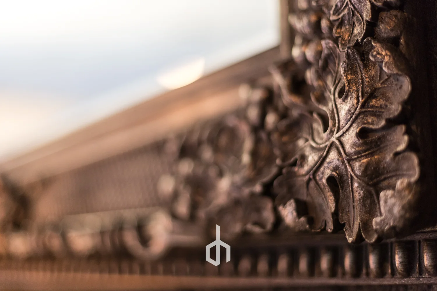 Close-up of a rusty metal door latch with a floral carved pattern on the surface.