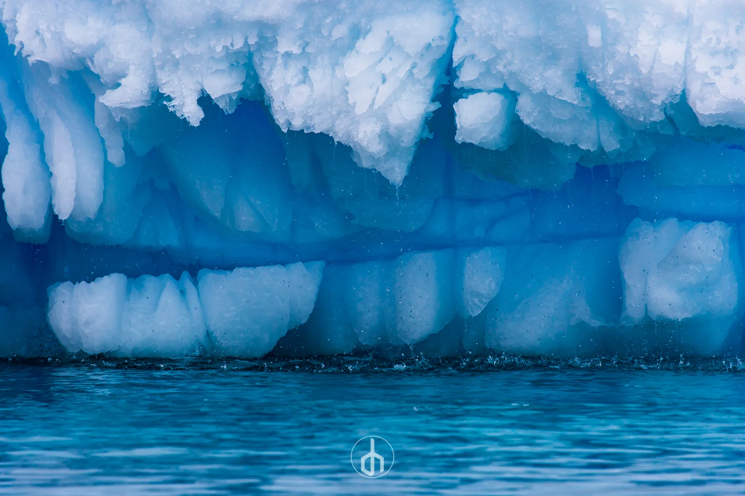 Close-up of a large iceberg with blue and white ice formations, melting into the ocean.