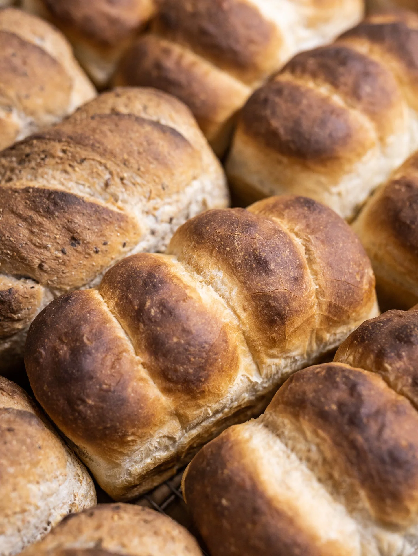 Close-up of freshly baked bread rolls with golden-brown crusts stacked together.