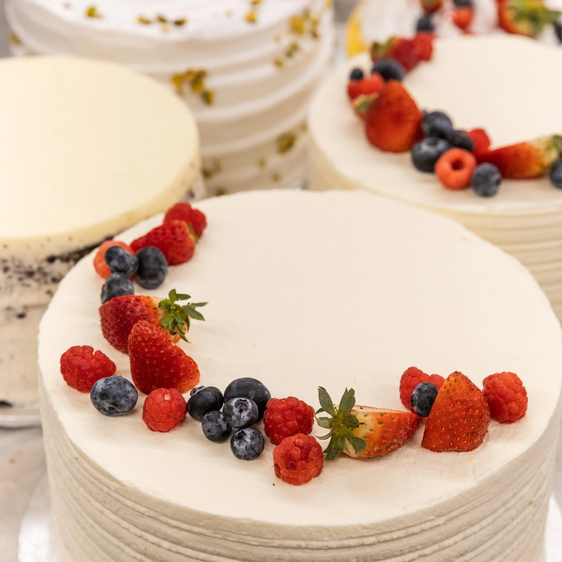 Close-up of a white cake with berries, including strawberries, blueberries, raspberries, and blackberries, decorated on the top edge.