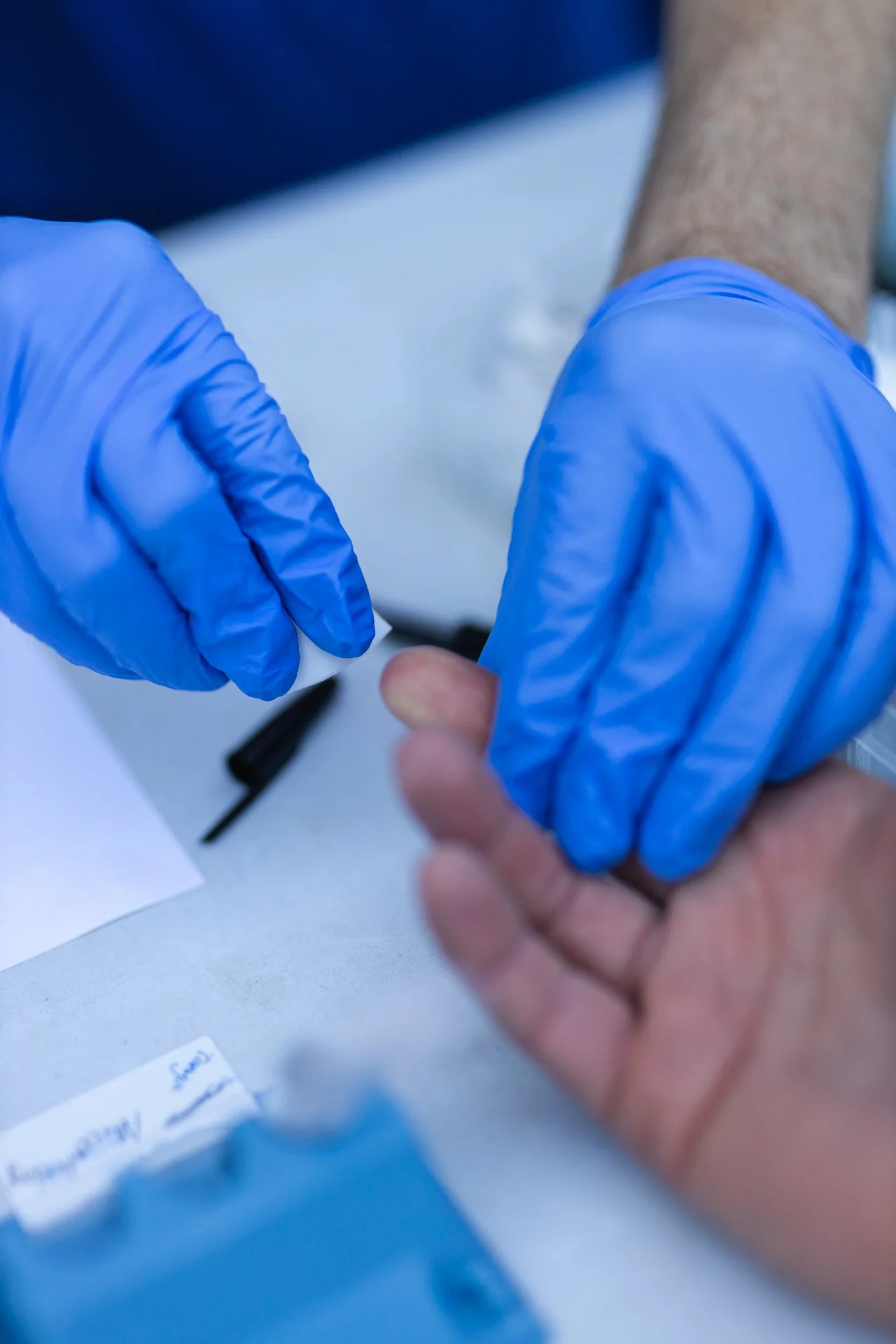 A healthcare professional with blue gloves administering a shot or vaccination to a person's arm.
