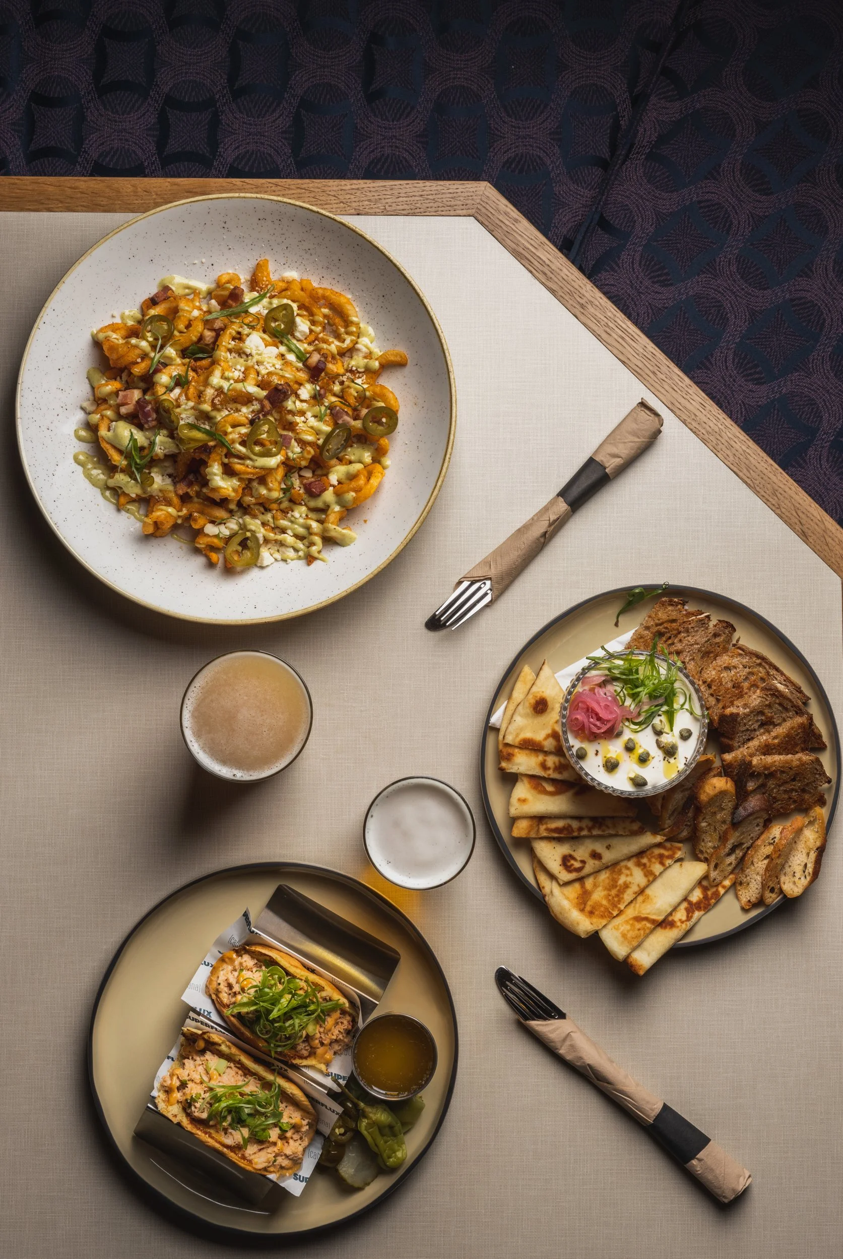 A table set with various Middle Eastern dishes including stuffed grape leaves, flatbread, dipping sauce, and fried items, with some drinks, napkins, and utensils.
