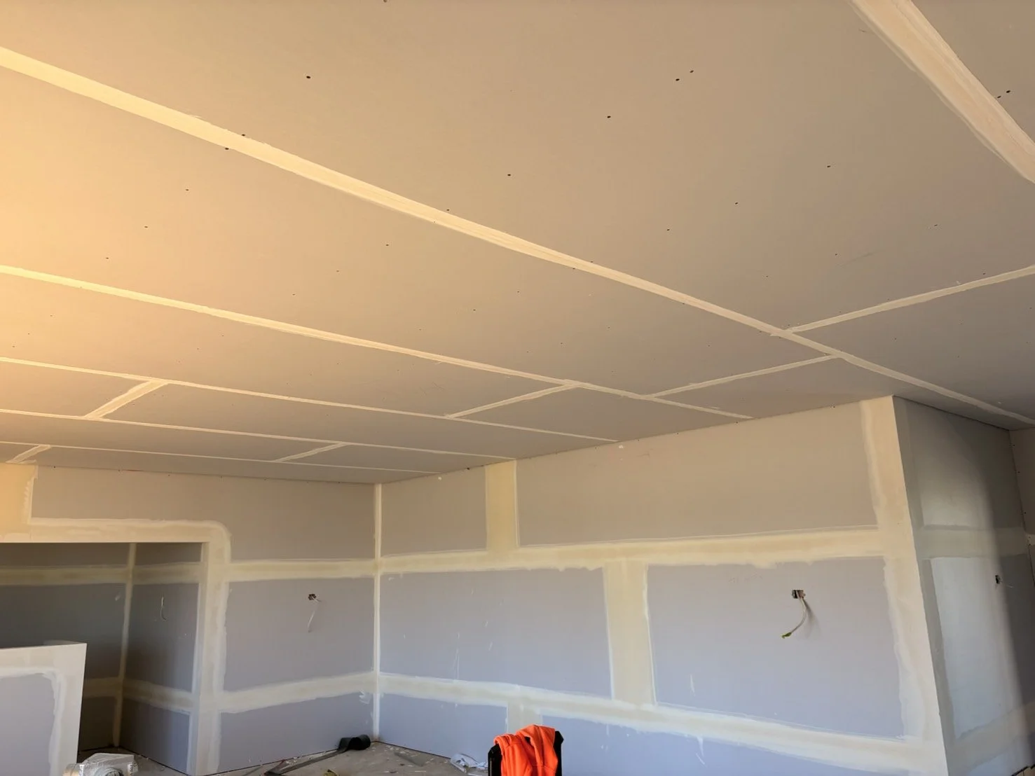 Room under construction with drywall installation, visible joints, and wiring