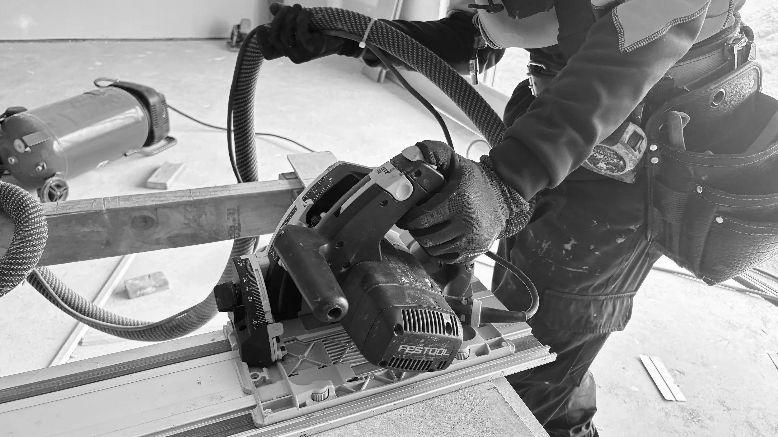 Person using a power saw with a guide on a workbench in a workshop.