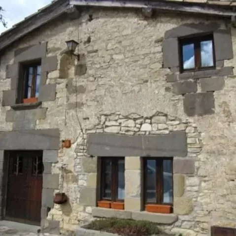 Casa de piedra con ventanas de madera y marcos de piedra.