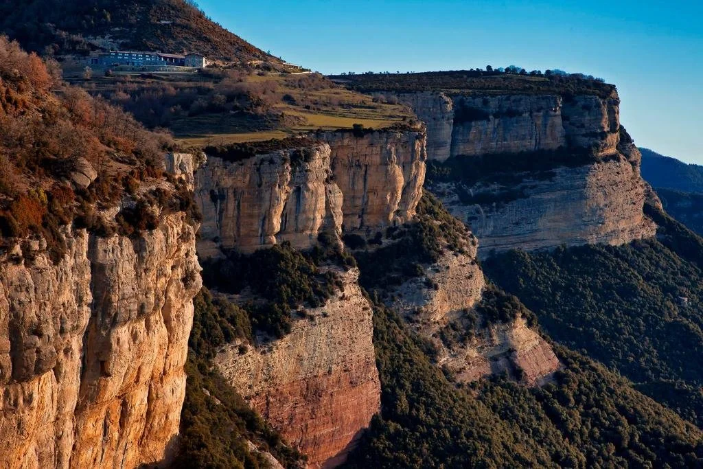 Formaciones rocosas y acantilados en las montañas con vegetación en Primer plano y fondo, cielo despejado.
