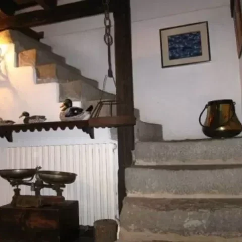 Escalones de piedra dentro de una casa antigua con decoraciones de madera y cuadros en la pared