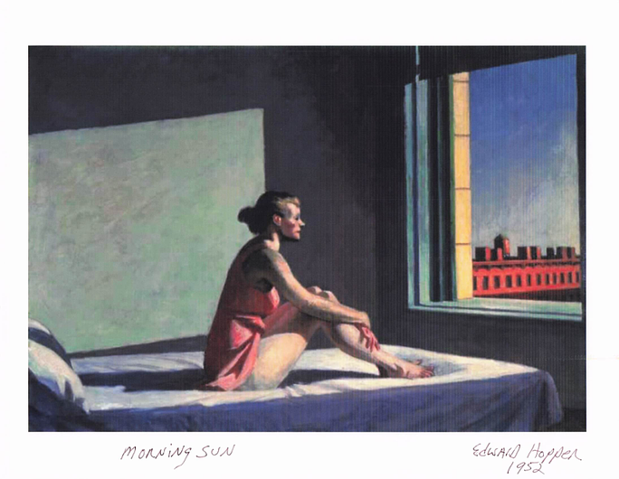 A woman in a pink dress sits on a bed, gazing out of a window at a city skyline during morning sunlight.