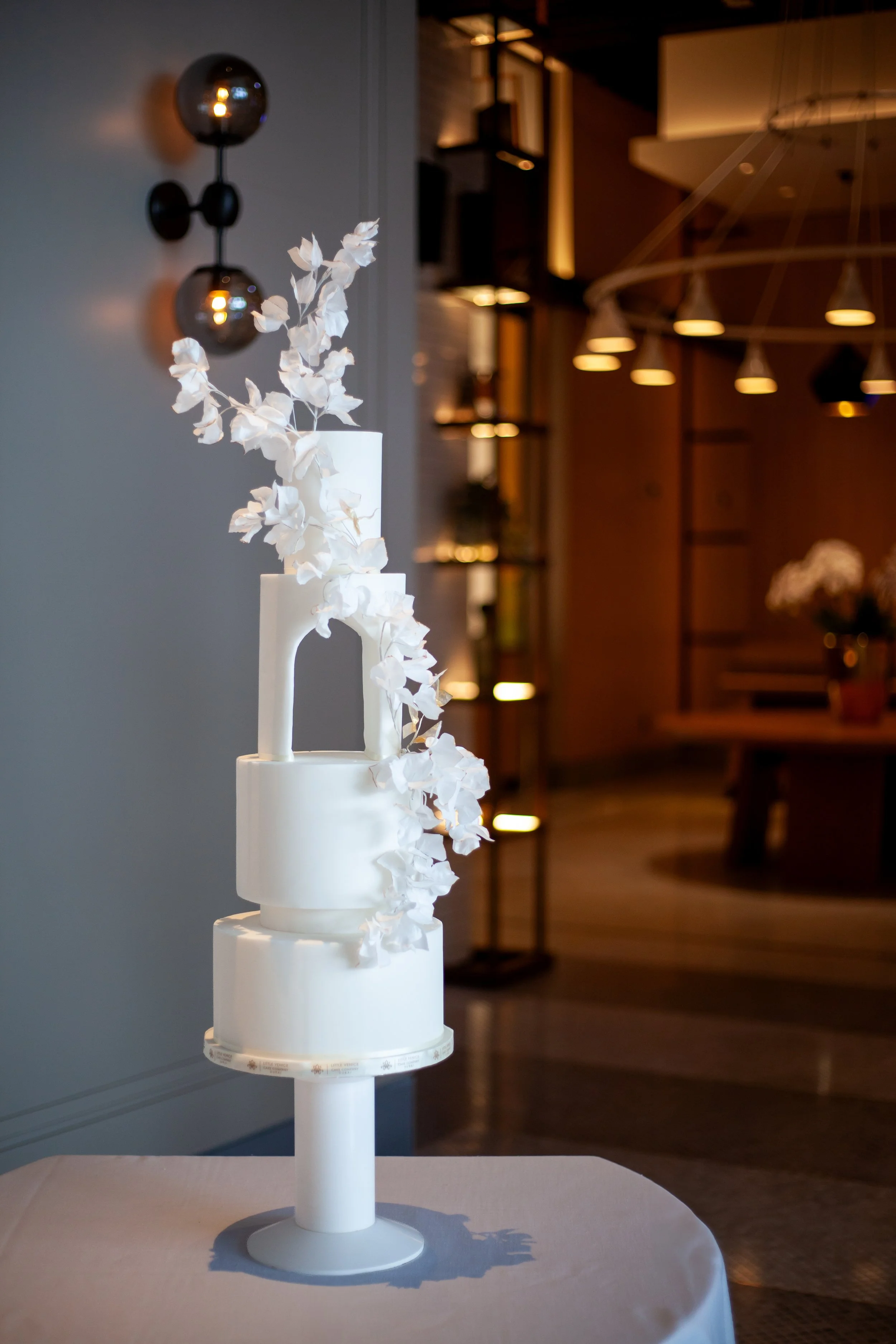 Modern multi-tier white wedding cake with sculptural floral details and an elegant minimalist silhouette.