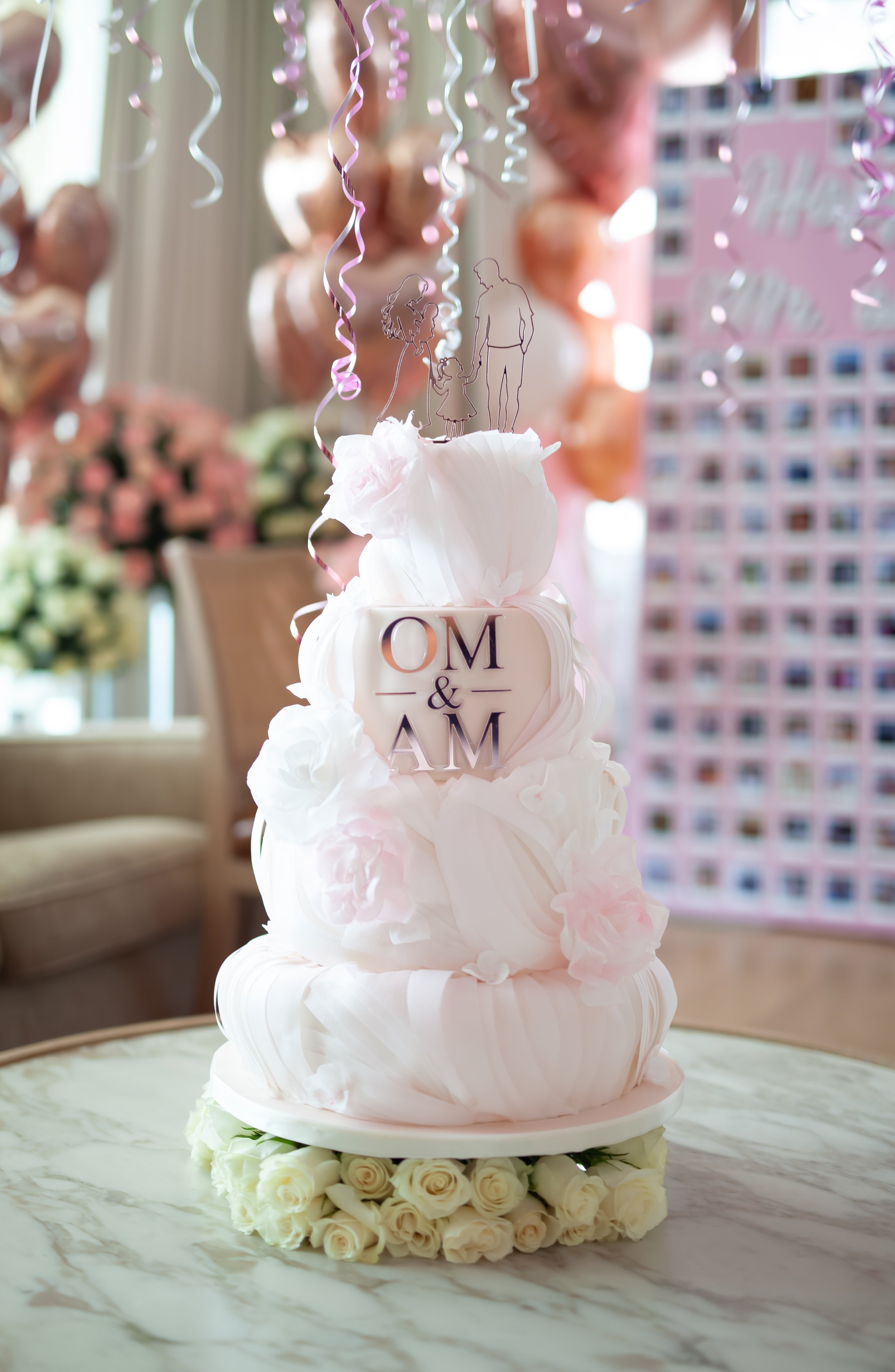 Bespoke wedding cake with pink sugar flowers and a personalised family silhouette topper.