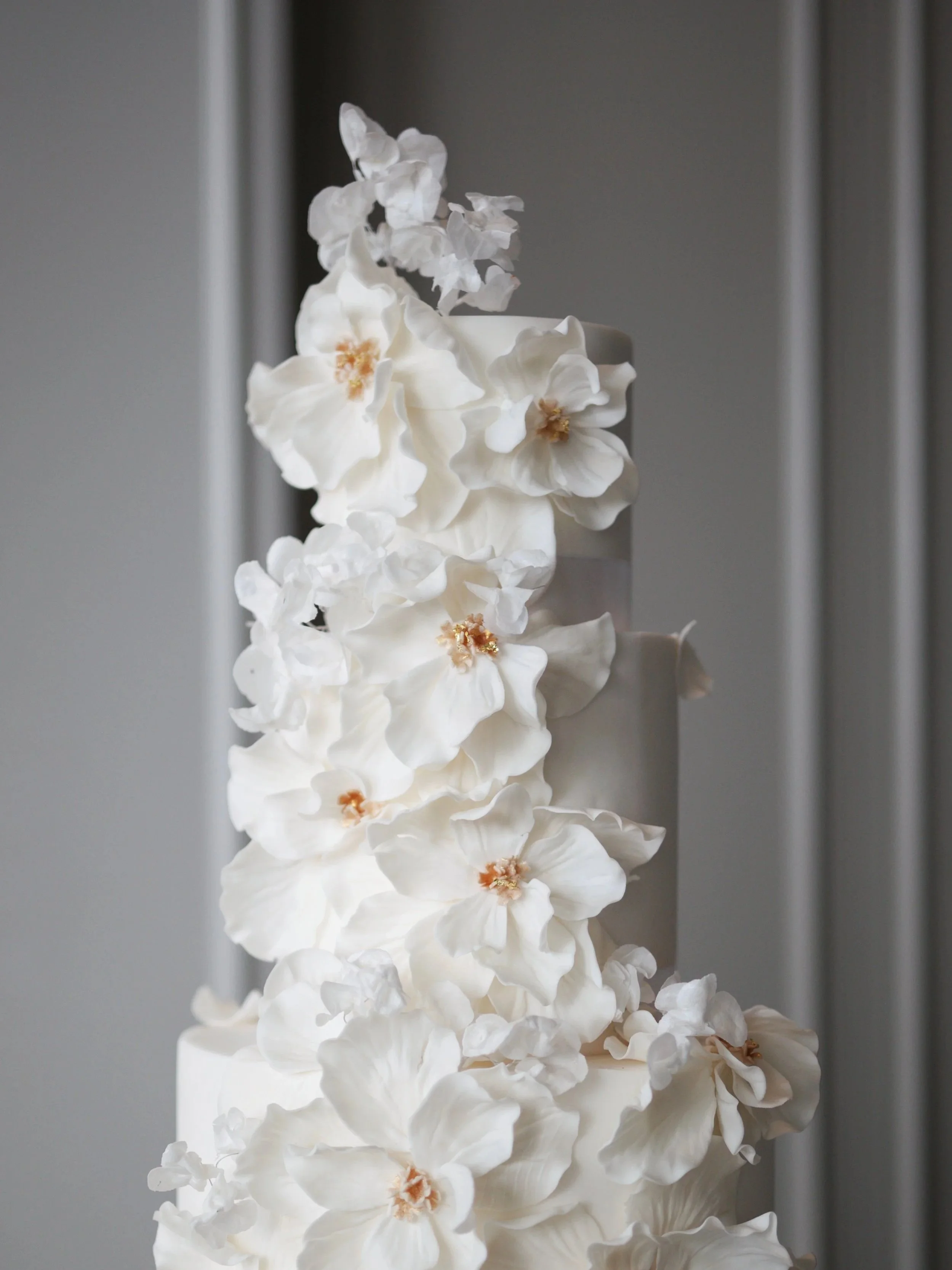 Contemporary white sculptural cake with dramatic oversized sugar flowers.