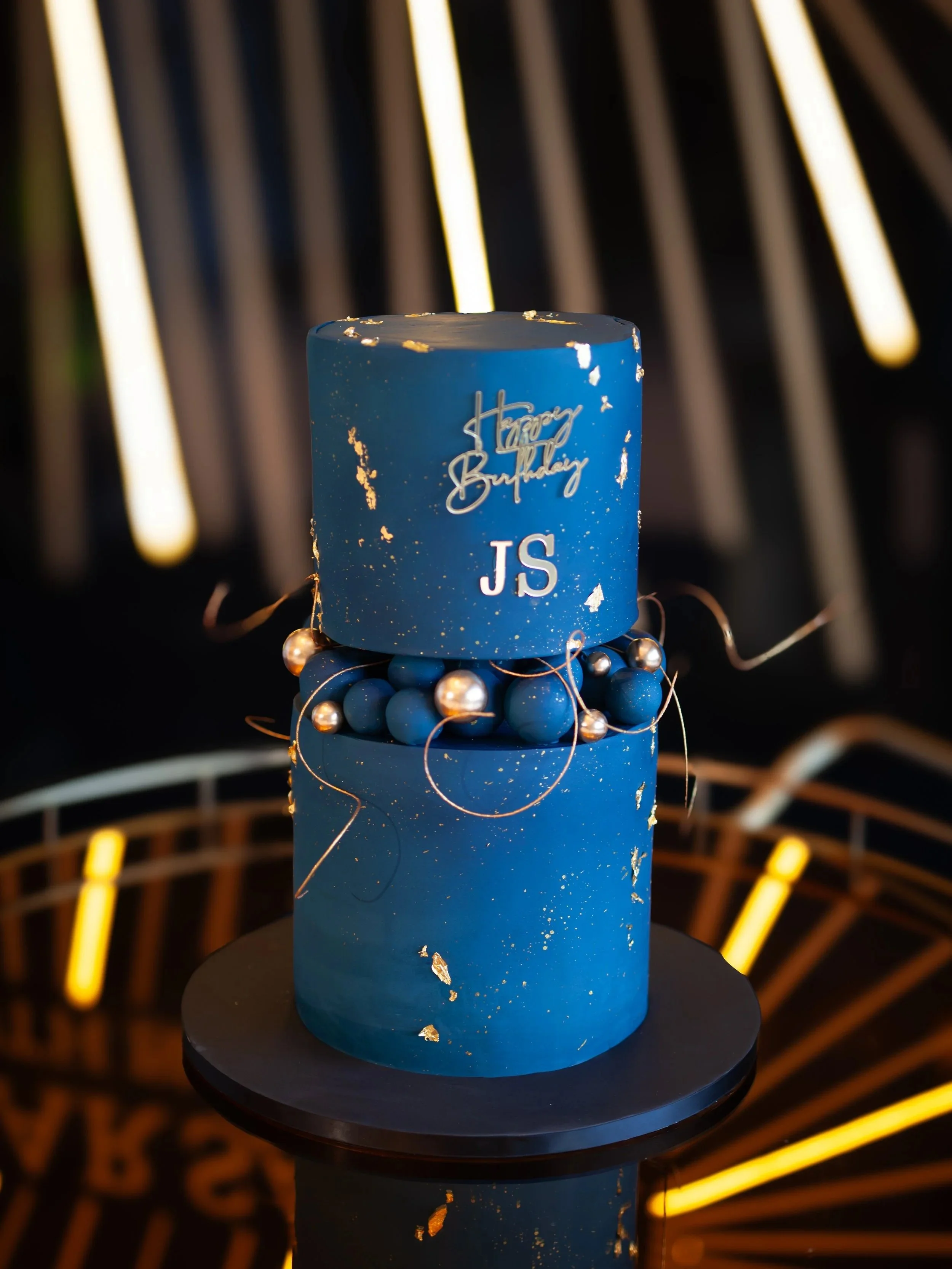 Contemporary blue birthday cake with elegant gold detailing and personalised design elements.