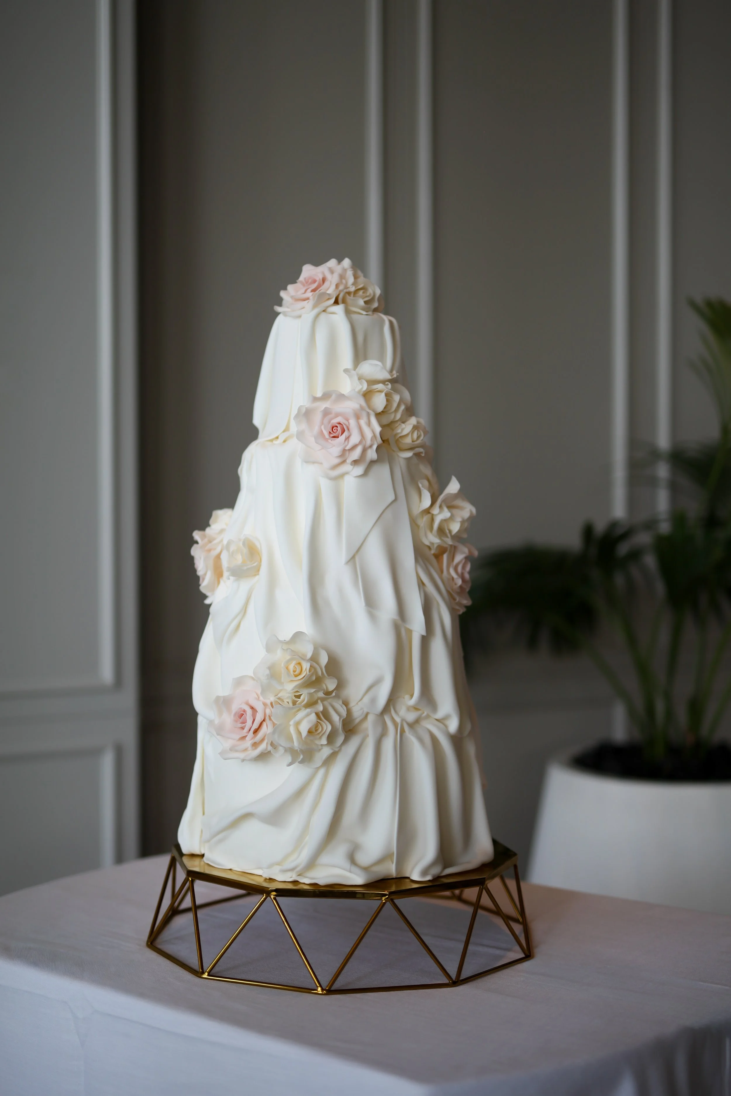 Contemporary white wedding cake with sculptural draping and delicate sugar flowers.