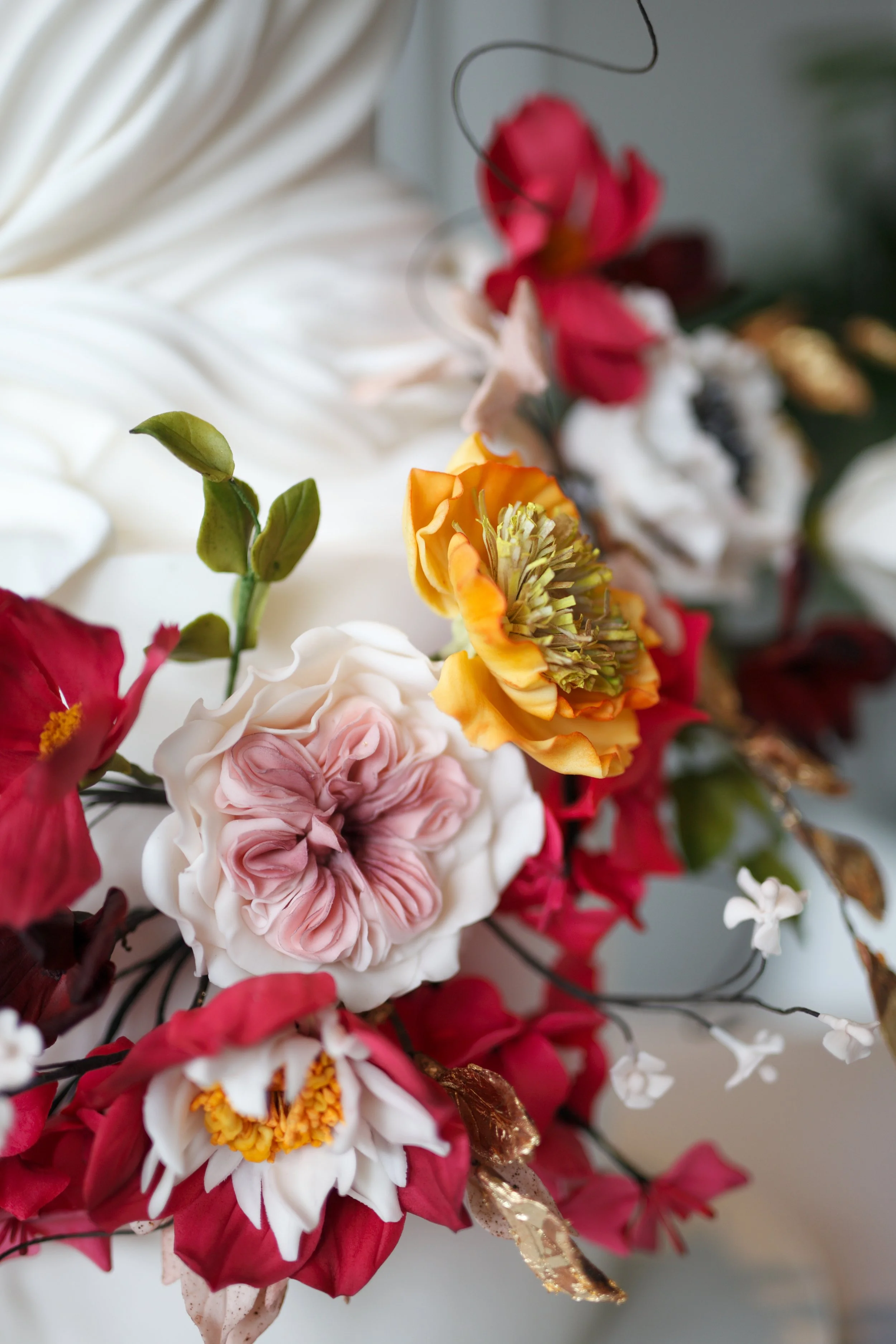 Close-up of vibrant handcrafted sugar flowers and foliage on a bespoke wedding cake.