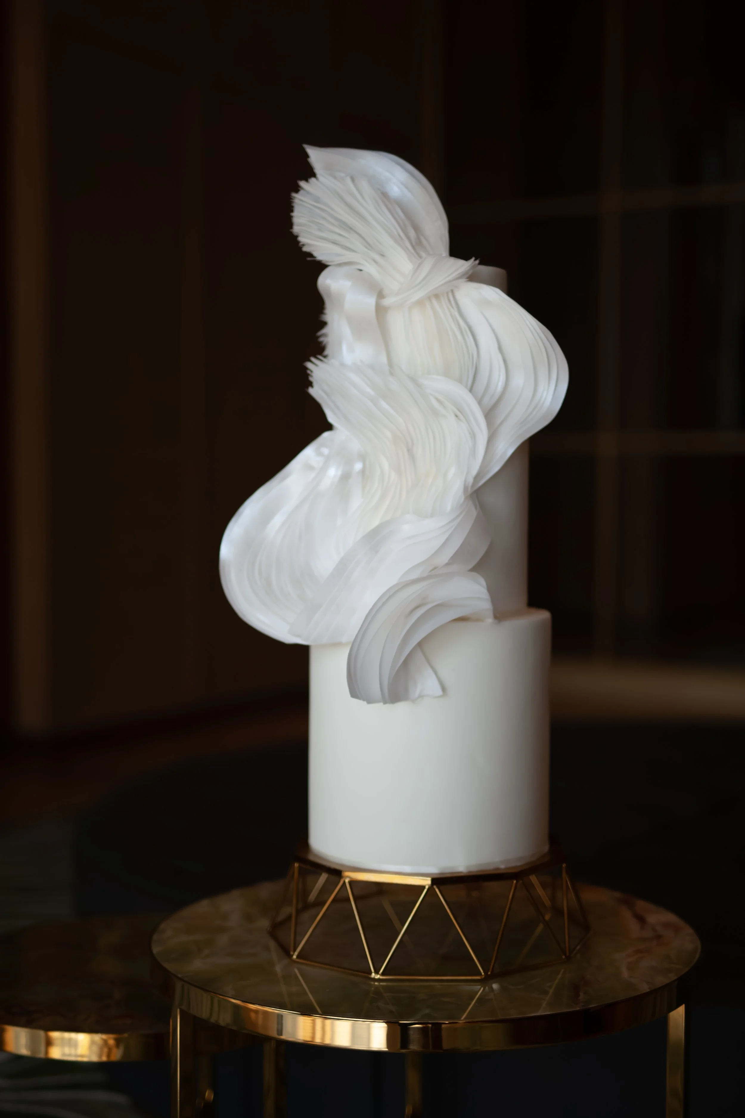 Contemporary sculptural white cake with flowing, layered edible forms of wafer paper.