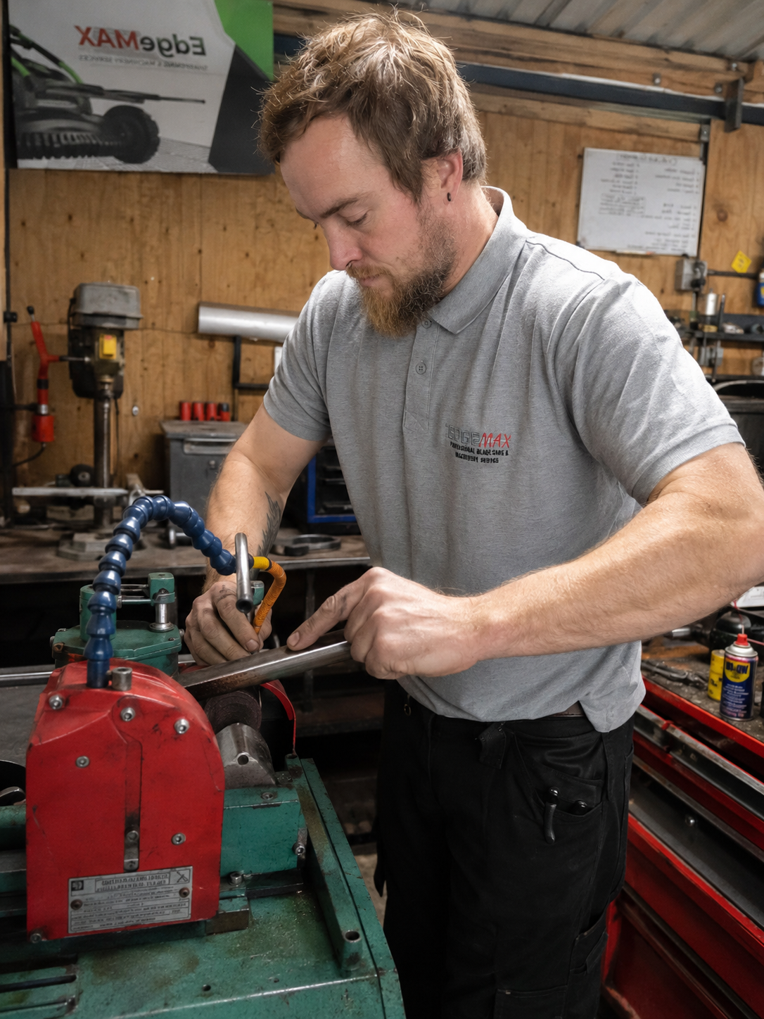 A man working in a workshop using a caliper on a metal rod, surrounded by tools and equipment.