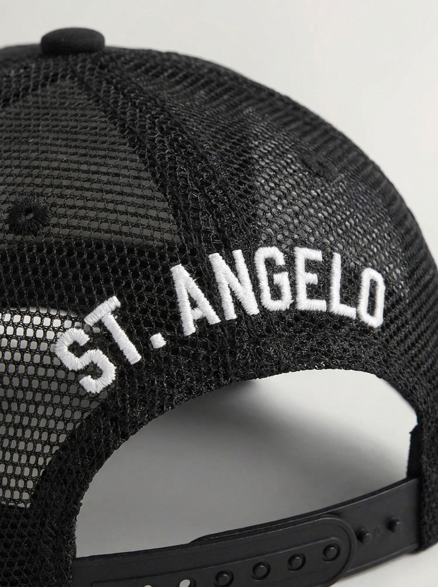 Close-up of a black mesh trucker hat with white embroidered text 'S.T. ANGELO' on the back.