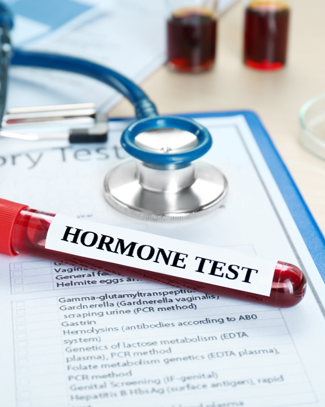 A medical scene with a blood sample labeled 'HORMONE TEST' on a table, a stethoscope, and two test tubes filled with dark liquid, along with medical documents.