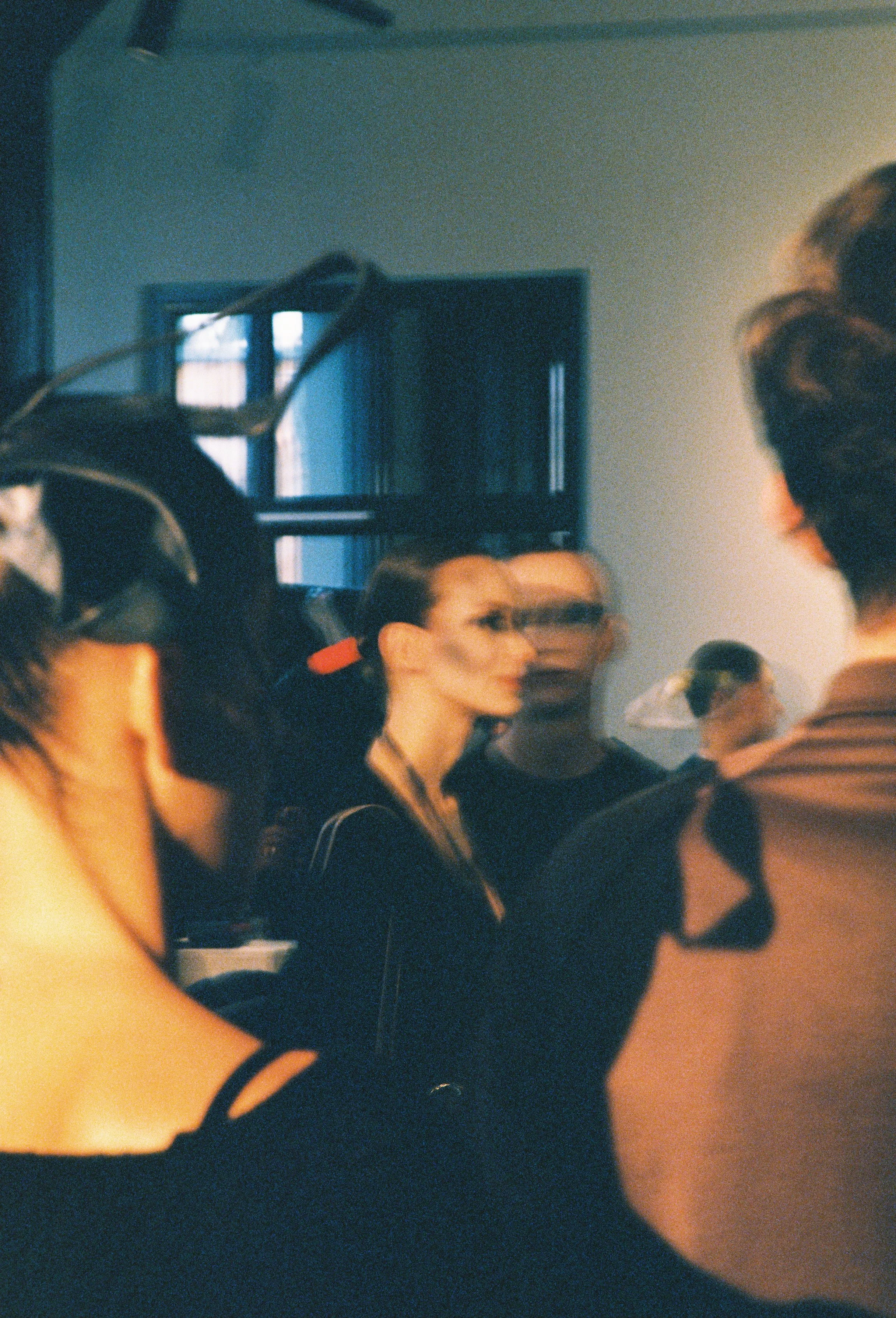 A group of people standing indoors, with some wearing glasses and casual clothing, on a possibly social or public occasion.
