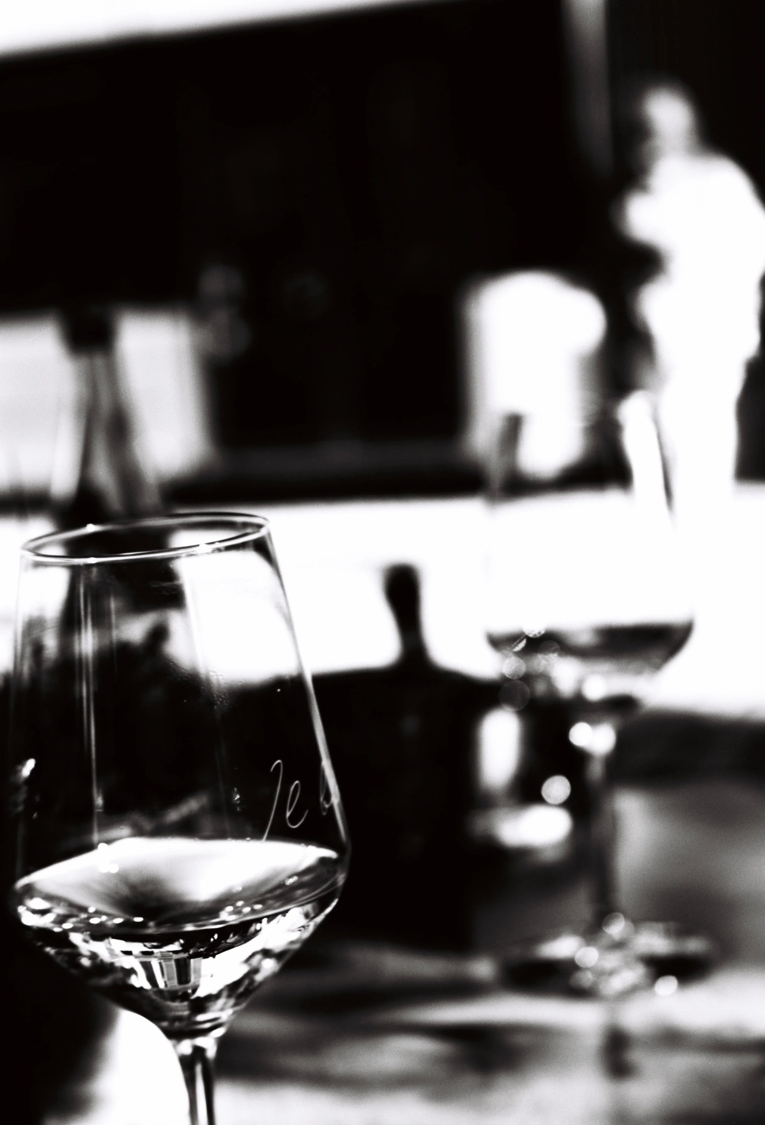 Close-up of empty wine glasses on a table, with a blurred background in black and white.