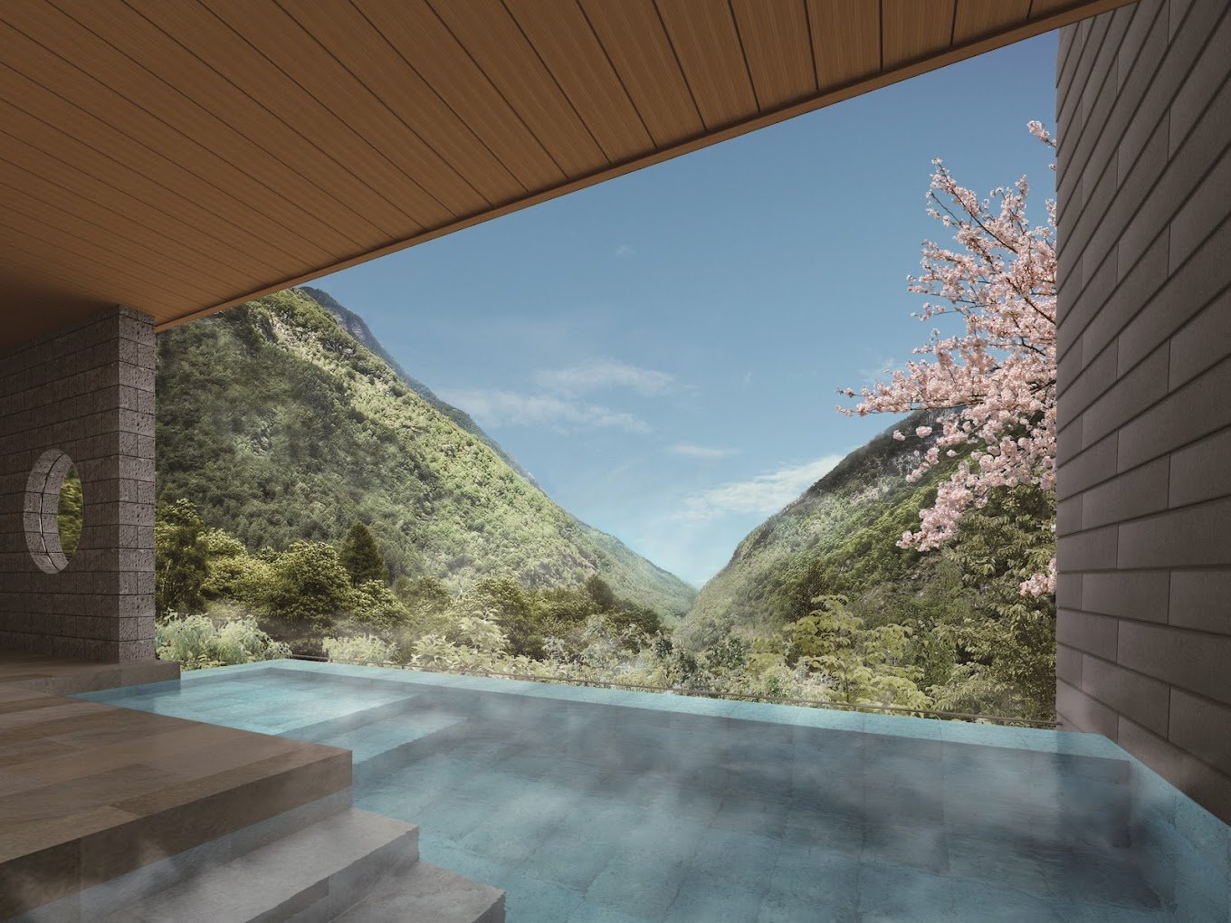 An outdoor infinity outdoor onsen pool overlooking lush green mountains and a flowering cherry blossom tree, under a wooden ceiling.