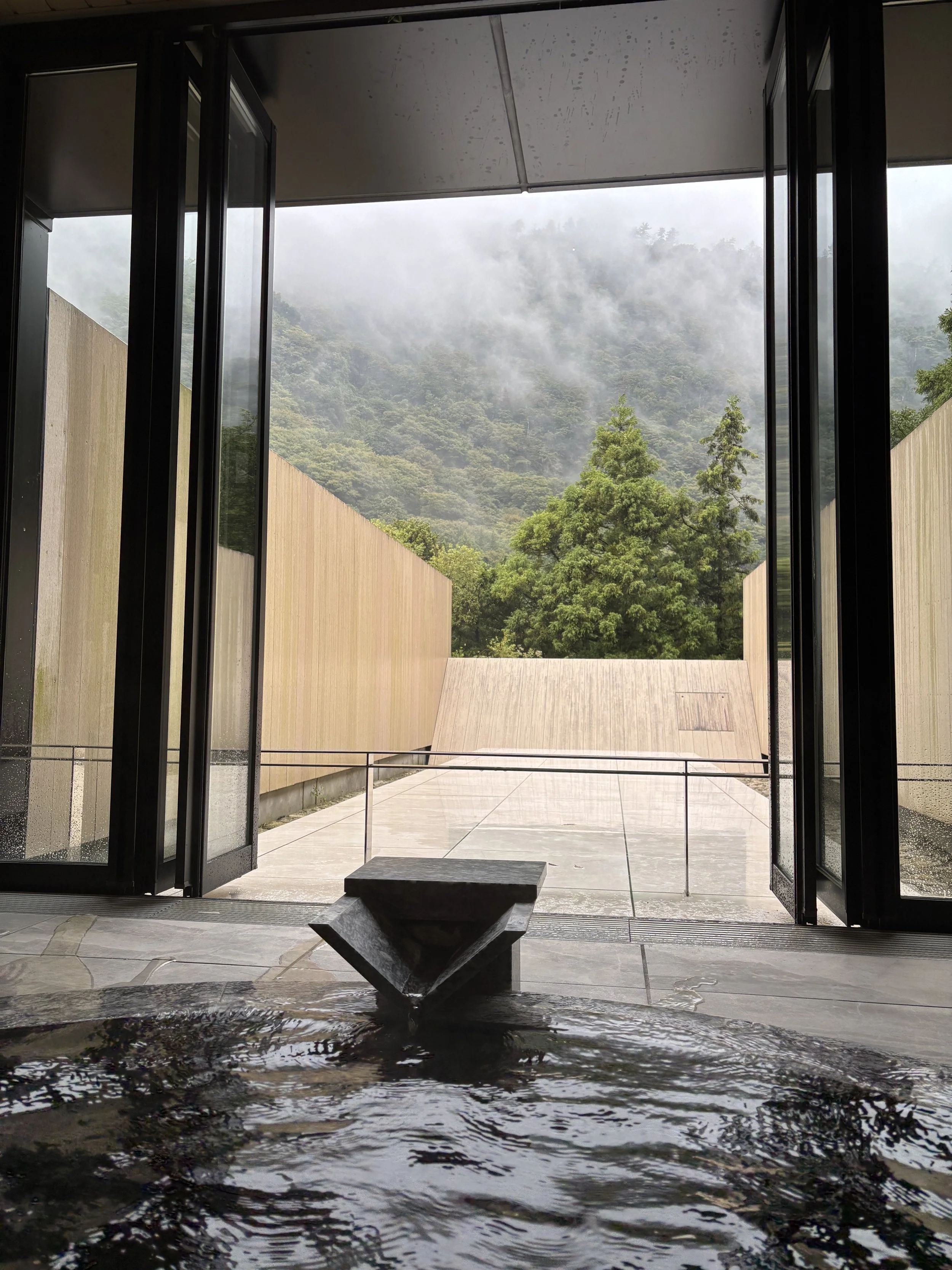 A modern traditional inn Ryokan in Hakone, with an onsen with a view on a mountain landscape with foggy clouds in the background.