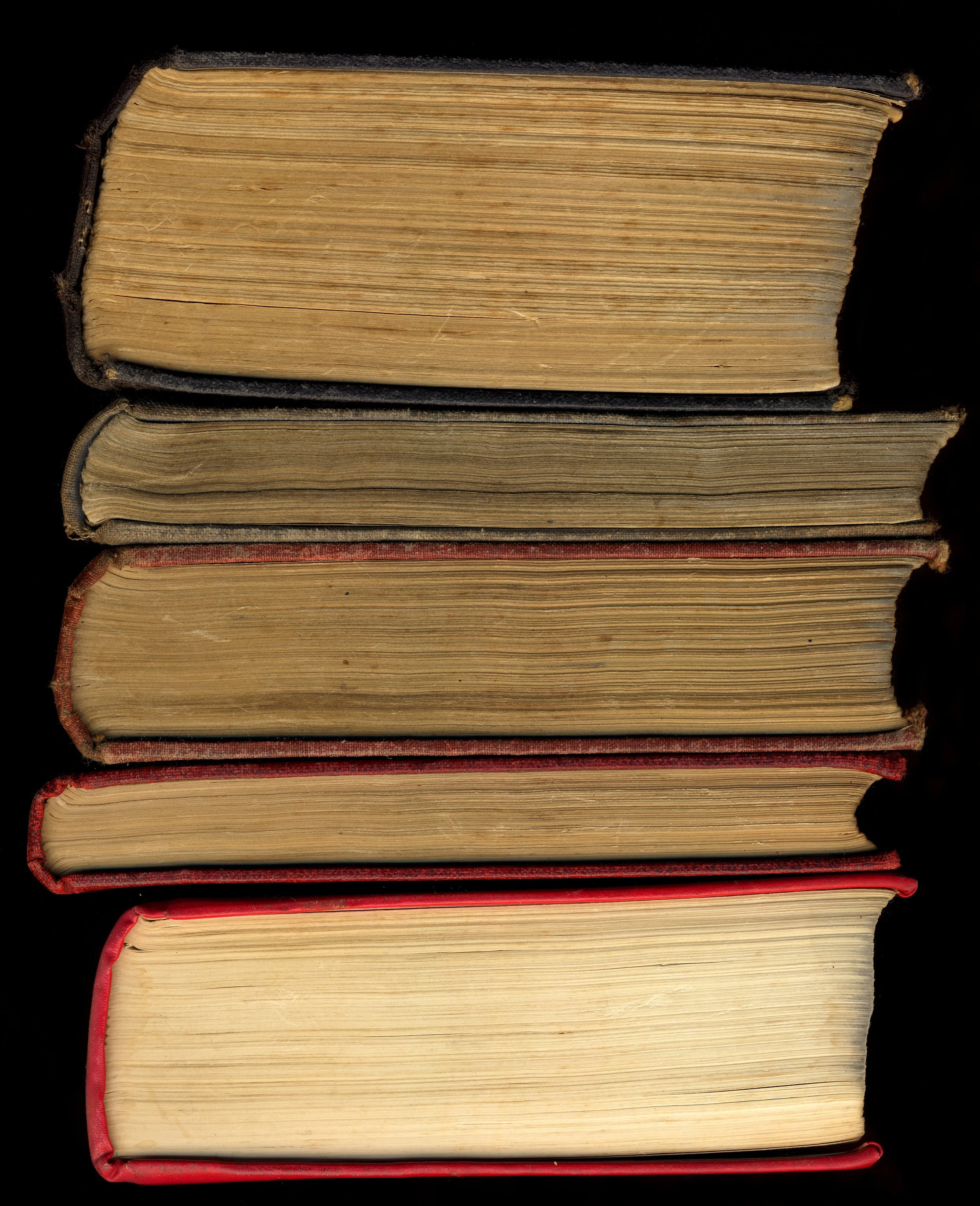 Stacked old hardcover books with worn pages and frayed edges on a black background.