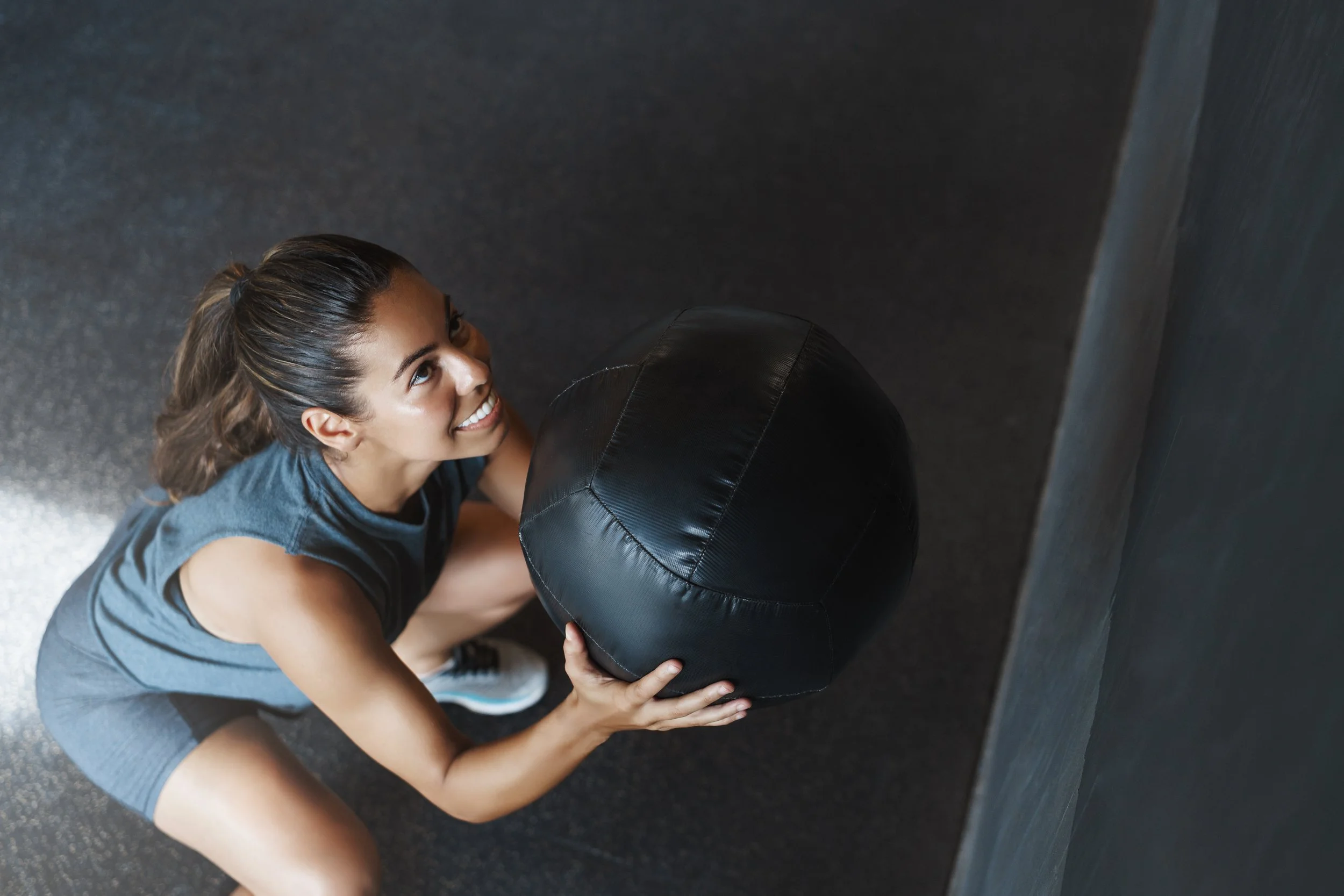 young-strong-woman-lifts-ball-up-as-perform-squats-exercise.jpg
