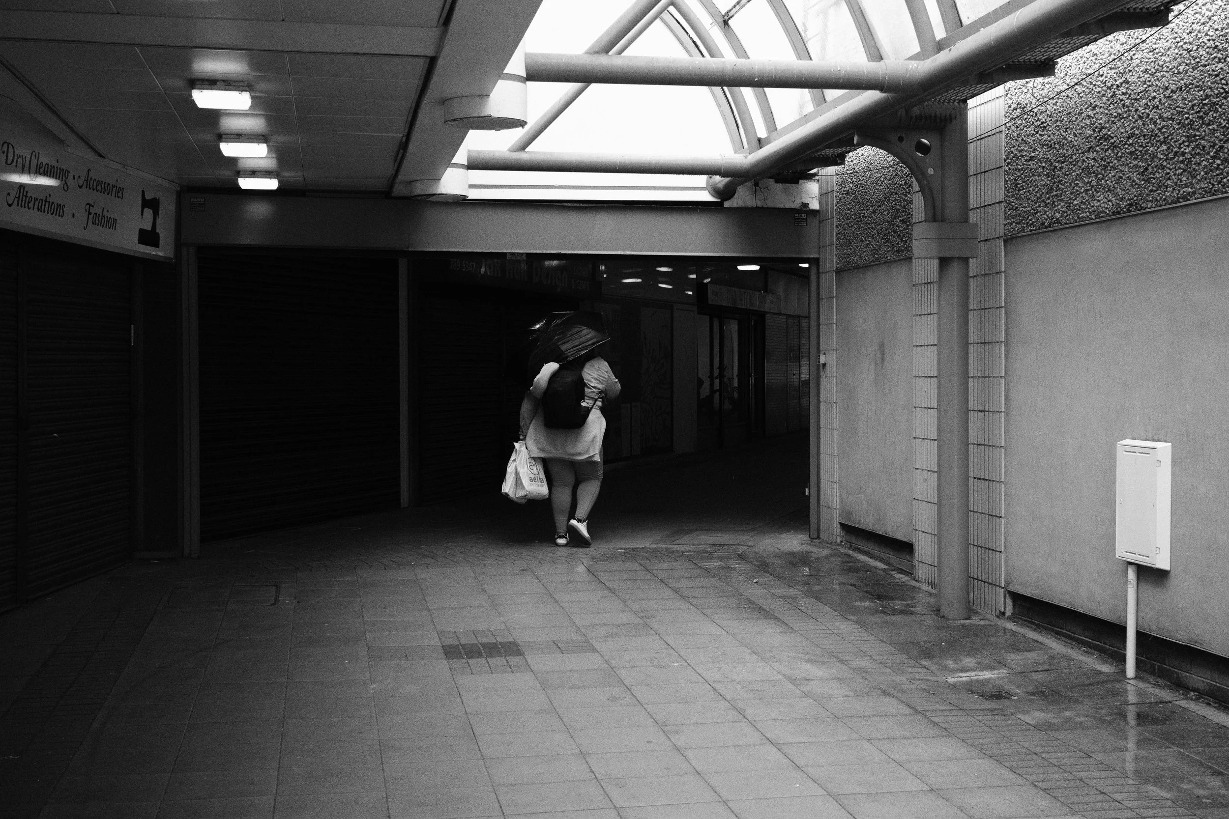 A woman walks into Eccles shopping centre with her umbrella still up