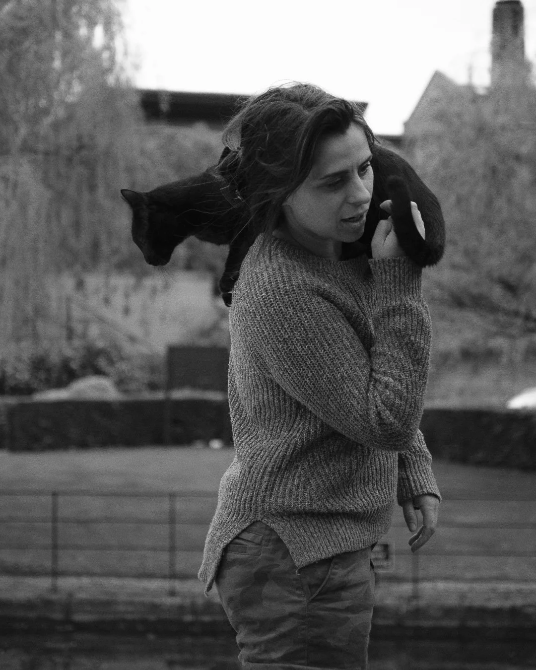 Black and white image of a woman being climbed on by a cat