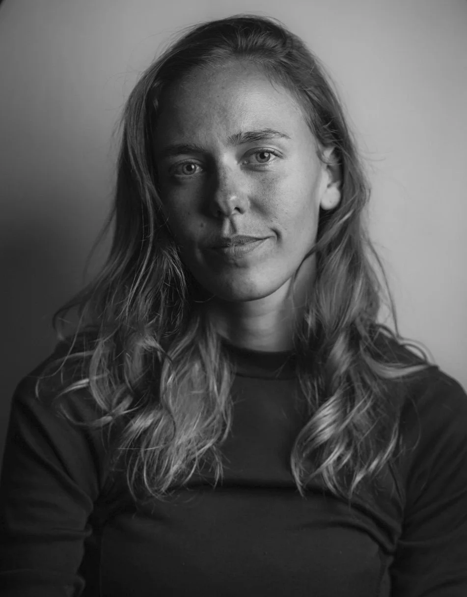Black and white portrait of a woman with wavy hair, wearing a dark shirt, looking at the camera with a slight smile.