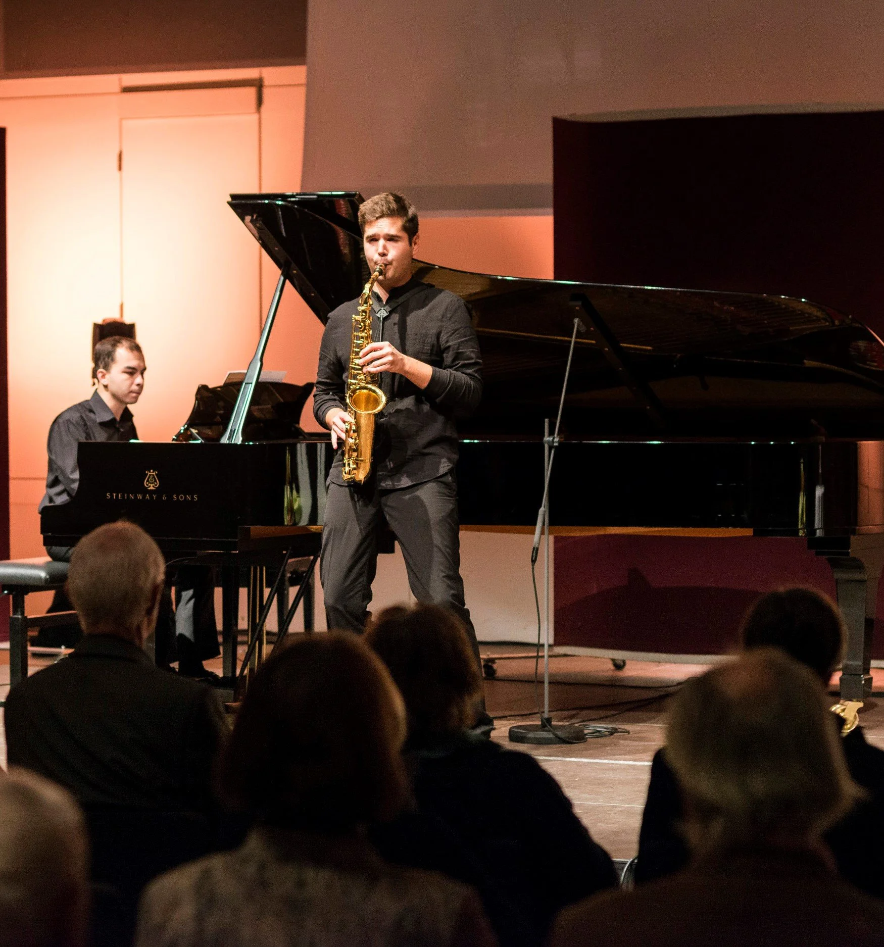 Ein Saxophonspieler und ein Pianist bei einem Live-Konzert in einem Konzertsaal.