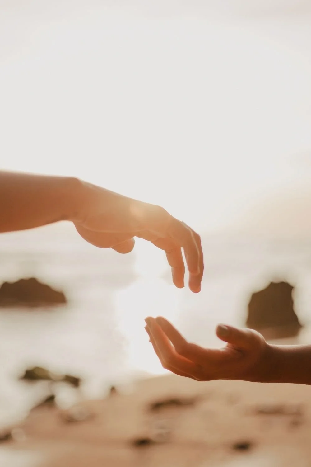 Two hands reaching toward each other in soft sunlight, symbolizing connection, trust, and support in emotional eating therapy with an emotional eating dietitian helping clients build a healthier relationship with food.