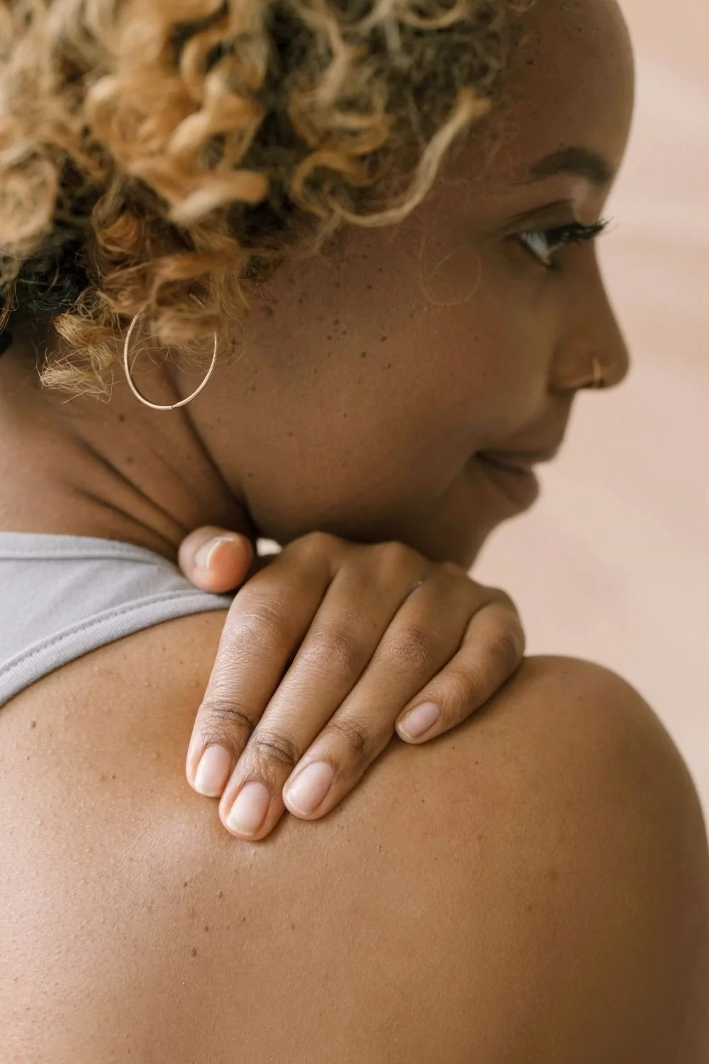 Close-up of a person gently holding their shoulder, representing self-care, somatic awareness, and the holistic support offered by a dietitian NYC specializing in integrative body health.