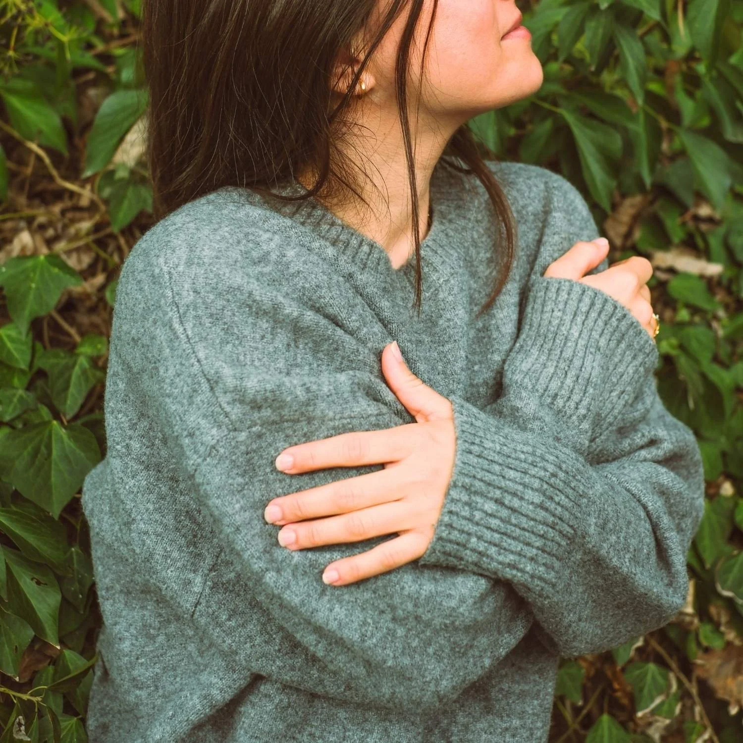Person outdoors gently hugging themselves in a self-compassionate pose, representing recovery support through eating disorder treatment online, guidance from an eating disorders dietitian, and emotional wellness practices.