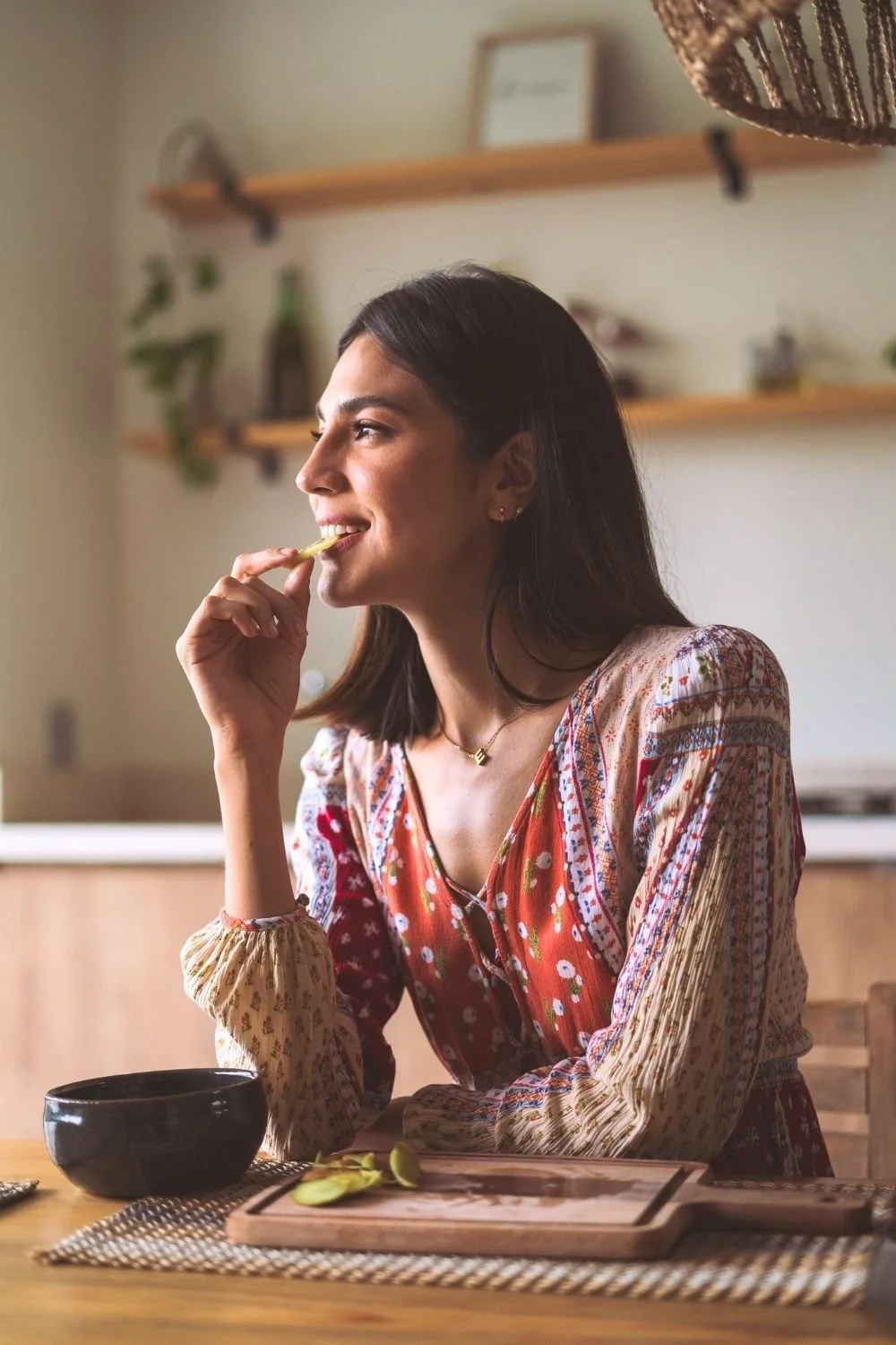 Person thoughtfully eating a healthy snack in a bright home setting, illustrating nutrition coaching and nutrition counseling online, mindful eating habits, and support for diet regulation and overall wellness.