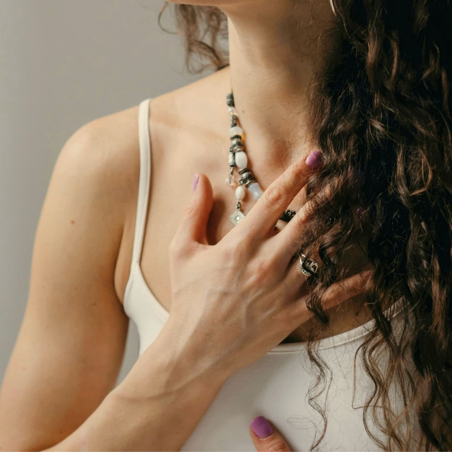 Person resting a hand on their chest in a moment of self-reflection, fostering body awareness, emotional connection, and nervous system regulation.