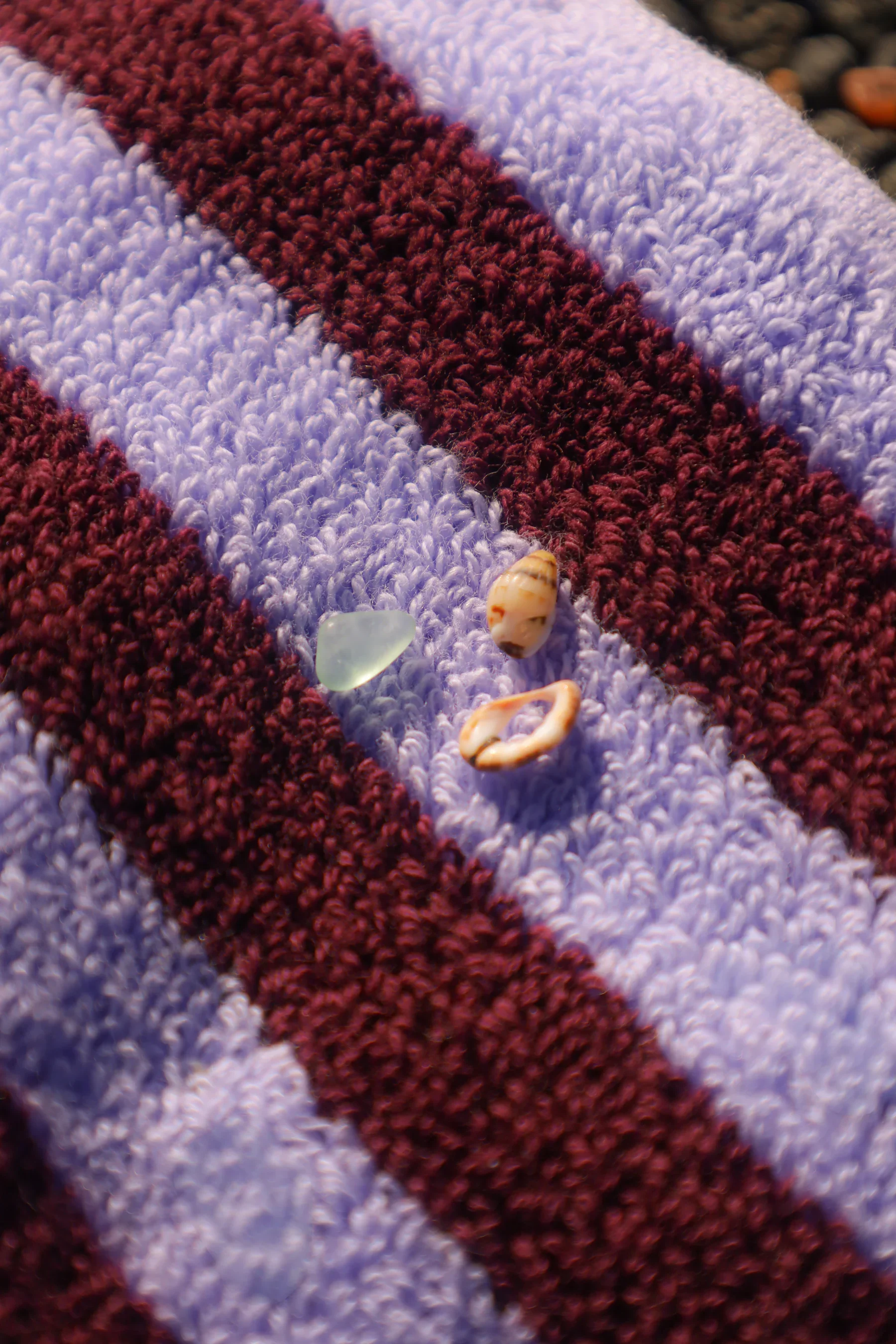 Close-up of a multicolored towel or fabric with small shells and other small objects placed on it.