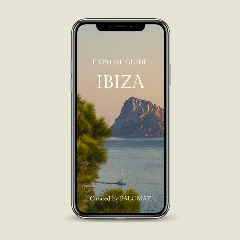 Smartphone displaying a travel guide for Ibiza with a scenic photo of a mountain, water, and a sailboat.