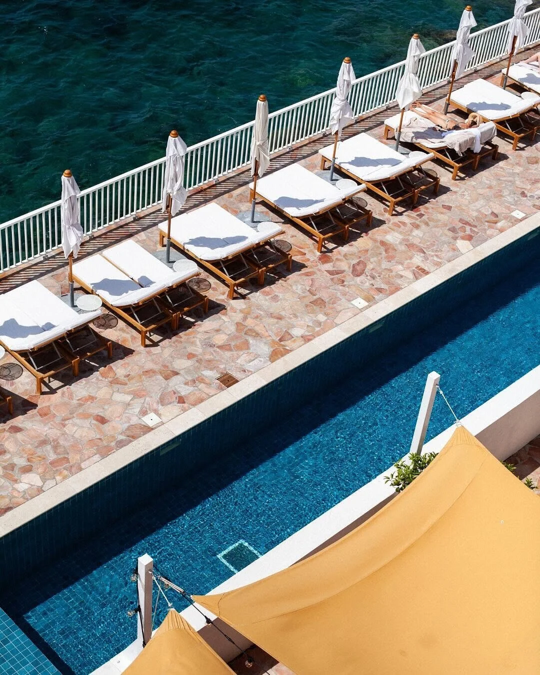 Poolside view with outdoor loungers and umbrellas overlooking the ocean.