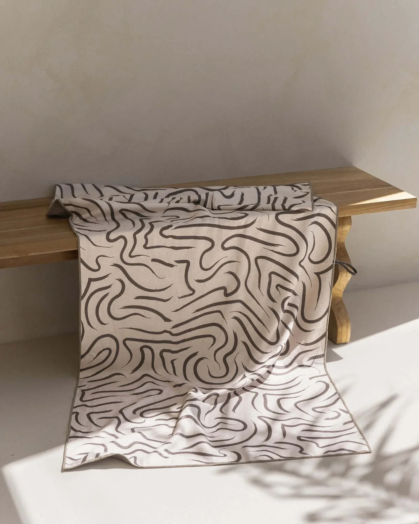 A wooden table with a black and white patterned cloth hanging over the front, against a plain wall background.